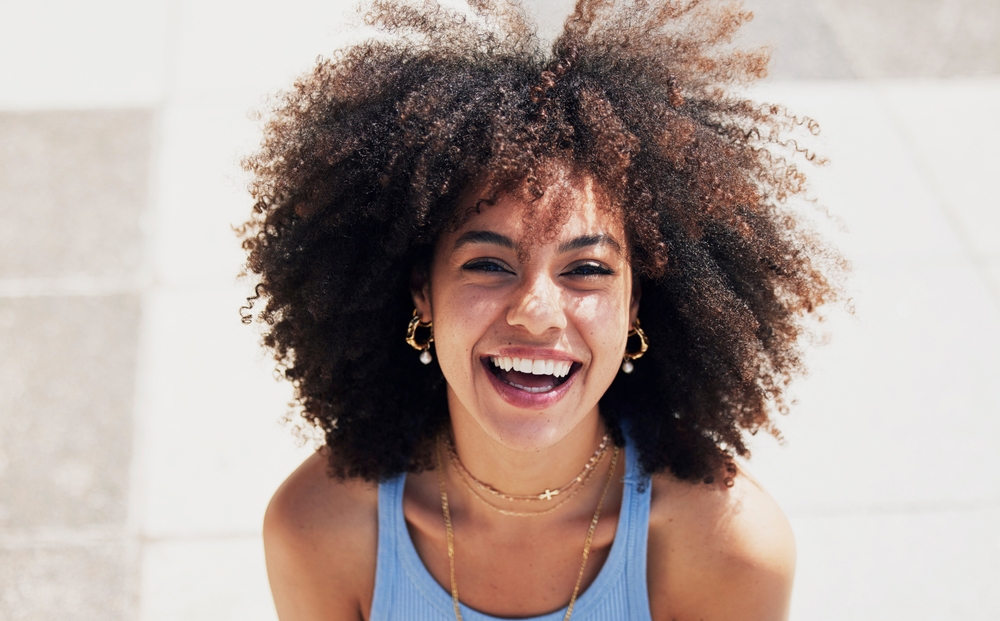 Woman with curly hair smiling showing healthy teeth Orthodontic dental care TX