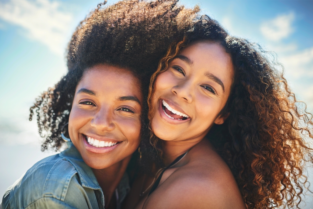 Two women smiling with bright healthy smiles dental services Woodlands TX