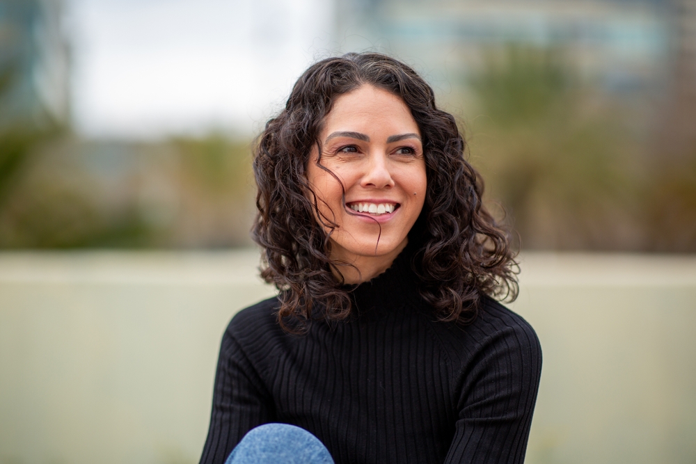 Woman with curly hair smiling naturally healthy smile Woodlands TX dentist