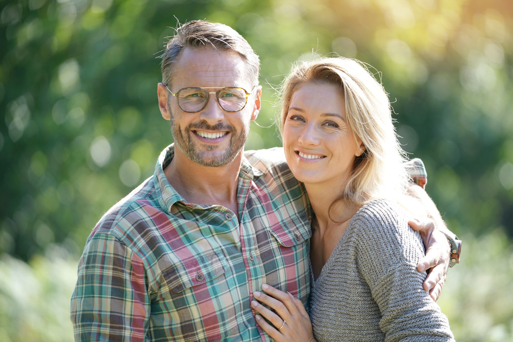 Middle-aged couple smiling outdoors healthy smiles Woodlands TX dental care